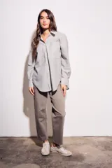 Camisa oversize color arena con rayas verticales marrones, de manga larga y cuello clásico.