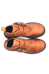 Botín negro de cuero con caña corta, suela track y ajuste con hebillas doradas.