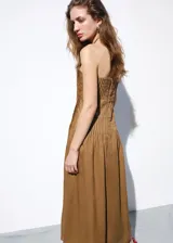 Vestido midi de ramio color marrón, sin tirantes con escote palabra de honor, diseño plisado en el corpiño y falda evasé.