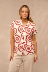 Blusa Magda de manga corta con escote en V y cuello mao. Diseño de corte recto en color blanco con estampado circular en tonos rojos y beige.