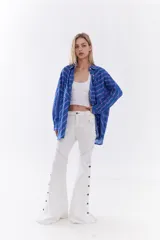 Pantalón de jean blanco de tiro medio, corte oxford, con costuras pespunteadas a contratono y aberturas laterales con botones en los bajos.