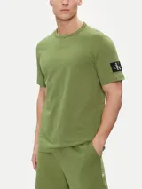 Remera verde oliva de algodón, corte clásico, cuello redondo y manga corta. Presenta una insignia con el monograma de Calvin Klein en la manga.