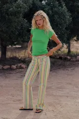 Jeans wide leg de tiro bajo con diseño de rayas verticales en tonos verde, amarillo y beige. Cuenta con cinco bolsillos, presillas para cinto y cierre frontal con cremallera y botón metálico.