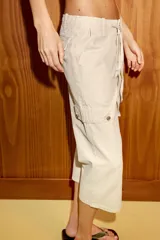 Pantalón capri de tiro medio con bolsillos cargo laterales, cierre frontal con cremallera, botón metálico y cordón ajustable en la cintura.