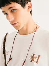 Remera de corte regular color beige con cuello redondo, mangas cortas y estampa frontal de pequeños nudos marineros en tono azul.