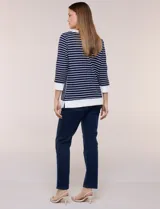 Buzo liviano de estilo deportivo-marinero y silueta semi holgada, confeccionado en tejido acanalado con diseño a rayas horizontales y verticales en azul marino y blanco. Cuenta con escote redondo amplio, cordón ajustable, bolsillo frontal tipo canguro, mangas tres cuartos con puños anchos y aberturas laterales en el ruedo.