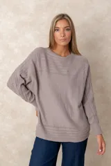 Buzo de punto color azul petróleo, con cuello redondo, mangas largas con puños ajustados y detalles de textura trenzada en la parte superior y el ruedo.