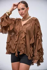 Blusa de gasa color marrón con volados en el frente y en las mangas largas. Presenta cierre frontal con botones y un diseño holgado con caída fluida.