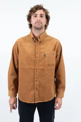 Camisa de pana color camel, de corte recto, con cuello abotonado y bolsillo en el pecho.