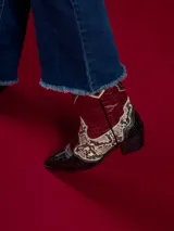 Botas texanas cortas de cuero sintético negro con detalles en animal print y cierre lateral.