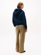 Buzo azul marino con capucha y cordón ajustable, confeccionado en algodón. Presenta logo de Tommy Hilfiger bordado en rojo en el pecho.