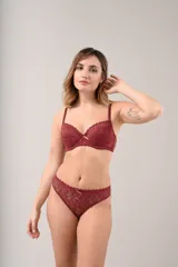 Conjunto de lencería compuesto por un soutien con aro y bombacha tipo vedetina, confeccionados íntegramente en encaje floral color beige. El soutien presenta breteles regulables y un pequeño lazo decorativo en el centro, mientras que la bombacha incluye un detalle de lazo a juego en la parte frontal.