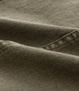 Pantalón flare de sarga color verde oliva, con cintura ancha, doble botón, cierre tradicional, trabillas, detalle de recortes y bolsillos.