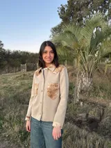 Camisa color beige de tejido de punto fino con apliques de cuero en cuello, hombros y bolsillos.
