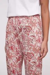 Pantalón de corte recto con estampado floral en tonos coral y verde sobre fondo crudo. Tiene bolsillos laterales y cintura elástica.