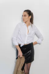 Camisa de corte clásico confeccionada en popelina blanca, con cuello camisero, cierre frontal de botones, bolsillo en el pecho y mangas largas con puños abotonados.