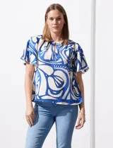 Blusa de seda fría con estampado abstracto en blanco y azul. Tiene cuello redondo con frunce, escote en V con botón y mangas cortas amplias.