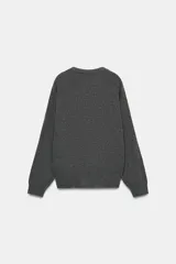 Jersey de punto liso color rojo, con escote en V profundo y mangas largas. Presenta terminaciones en rib en el cuello, puños y ruedo.