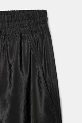 Pantalón negro de tiro medio con acabado brillante, cintura elástica ajustable con cordones y puños elásticos en los tobillos.