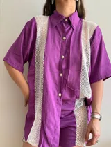 Camisa lila con paneles de red blanca en los laterales.
