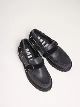 Mocasines de cuero negro con plataforma, diseño tipo náutico con costuras reforzadas en la puntera, detalle de tira sobre el empeine con apliques metálicos y argollas laterales.