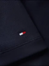 Remera de manga corta Tommy Hilfiger en color azul marino, con cuello redondo y bolsillo de parche en el pecho que presenta un detalle de línea horizontal con los colores distintivos de la marca. Incluye el logo de la bandera bordado en la manga izquierda.