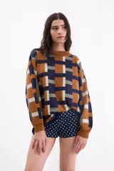 Sweater de tejido de punto con diseño geométrico a cuadros en tonos beige, terracota, bordó y celeste, de corte holgado, manga larga y cuello redondo.
