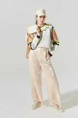 Pantalón de terciopelo color nude, de tiro alto, con cintura elástica en la espalda, cierre frontal, bolsillos laterales y piernas anchas.