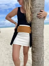 Minifalda blanca con aplique de cuero marrón con botones plateados.