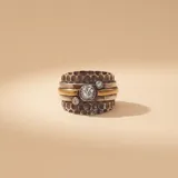 Anillo ancho de diseño artesanal compuesto por bandas de plata 925 con textura martillada y una banda central de oro. Presenta tres circonias engastadas en el frente.