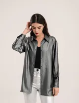 Camisa oversized con terminación metalizada color gris plomo. Tiene botones a tono en el delantero, largo por debajo de la cadera y tajos a los costados.