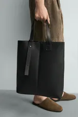 Bolso tipo shopper de diseño minimalista en color negro, con estructura vertical, doble asa de hombro y detalle de tira decorativa frontal con cierre magnético.