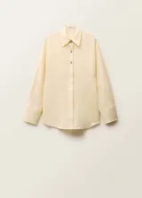 Camisa de lino color crema con cuello camisero, cierre frontal con botones metálicos y mangas largas con puños abotonados.