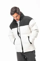 Campera puffer con diseño bicolor, presentando la parte superior en color negro y la parte inferior en color blanco. Cuenta con cuello alto, cierre frontal completo y bolsillos laterales con detalles en negro.