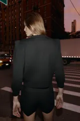 Chaqueta de punto color negro con cuello redondo, manga por debajo del codo con hombros marcados y acabados en rib. Cierre frontal con botones dorados.