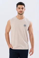 Musculosa beige jaspeado de corte clásico, con cuello redondo y diseño sin mangas. Presenta un pequeño estampado circular en el pecho con temática costera y la inscripción 'Paradise Bound'.