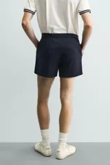Shorts de corte sastrero confeccionados en tejido de piqué elástico, con cierre frontal de cremallera y gancho metálico oculto, y bolsillos laterales.