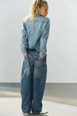 Jeans de tiro medio con diseño baggy, de pernera ancha y corte holgado. Cuenta con cinco bolsillos, trabillas para cinto y cierre frontal con cremallera y botón metálico.