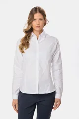 Camisa de tejido Oxford lisa y color blanco, con cuello camisero, cierre frontal de botones y mangas largas con puños abotonados.