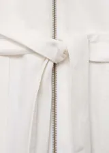 Mono largo blanco de algodón con cuello camisero, manga corta, cierre frontal con cremallera, cinturón desmontable y bolsillos laterales.