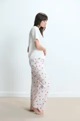 Pijama compuesto por una remera de cuello redondo en color blanco con un pequeño estampado de labios rojos en el pecho y un pantalón largo de corte holgado con estampado de rayas verticales y labios rojos sobre fondo claro.