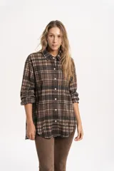 Camisa de corte oversize con estampado de cuadros en tonos marrones y beige. Presenta cuello clásico, cierre frontal con botones y mangas largas con puños simples.