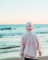 Hoodie de corte oversize color rosado, con capucha, mangas largas y estampa trasera con la inscripción "Glassy Waves Surf Company".