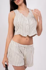 Short de vestir color gris con finas rayas verticales blancas, tiro alto, pinzas delanteras, bolsillos laterales y ruedo con dobladillo. Cierre frontal con botón y cremallera.