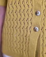 Cardigan de punto color tostado, de manga corta y cuello redondo, con cierre frontal de botones y diseño texturizado.