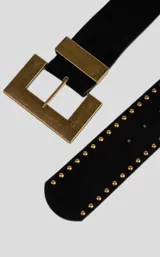 Cinturón negro de cuero con hebilla rectangular dorada y tachas doradas.