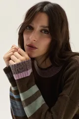 Sweater tejido de lambswool color beige, con cuello redondo y puños acampanados con rayas de colores (marrón, mostaza, bordó y beige). Incluye un detalle de temporada hecho a mano en la espalda.