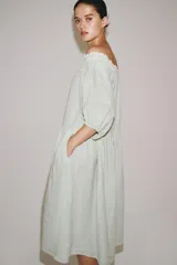 Vestido midi confeccionado en lino 100%, con escote recto elástico estilo hombros descubiertos, mangas abullonadas y detalle de pliegues en la cintura. Cuenta con bolsillos laterales ocultos y bajo asimétrico.