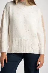 Polera de punto con diseño oversize, color blanco con motas multicolores. Presenta cuello alto y paneles laterales en las mangas con textura acanalada en tono beige.