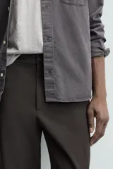 Pantalón de corte regular fit, color negro, confeccionado en tejido elástico. Presenta cintura elástica, cierre frontal con cremallera y botón, bolsillos laterales y bolsillos traseros de vivo.